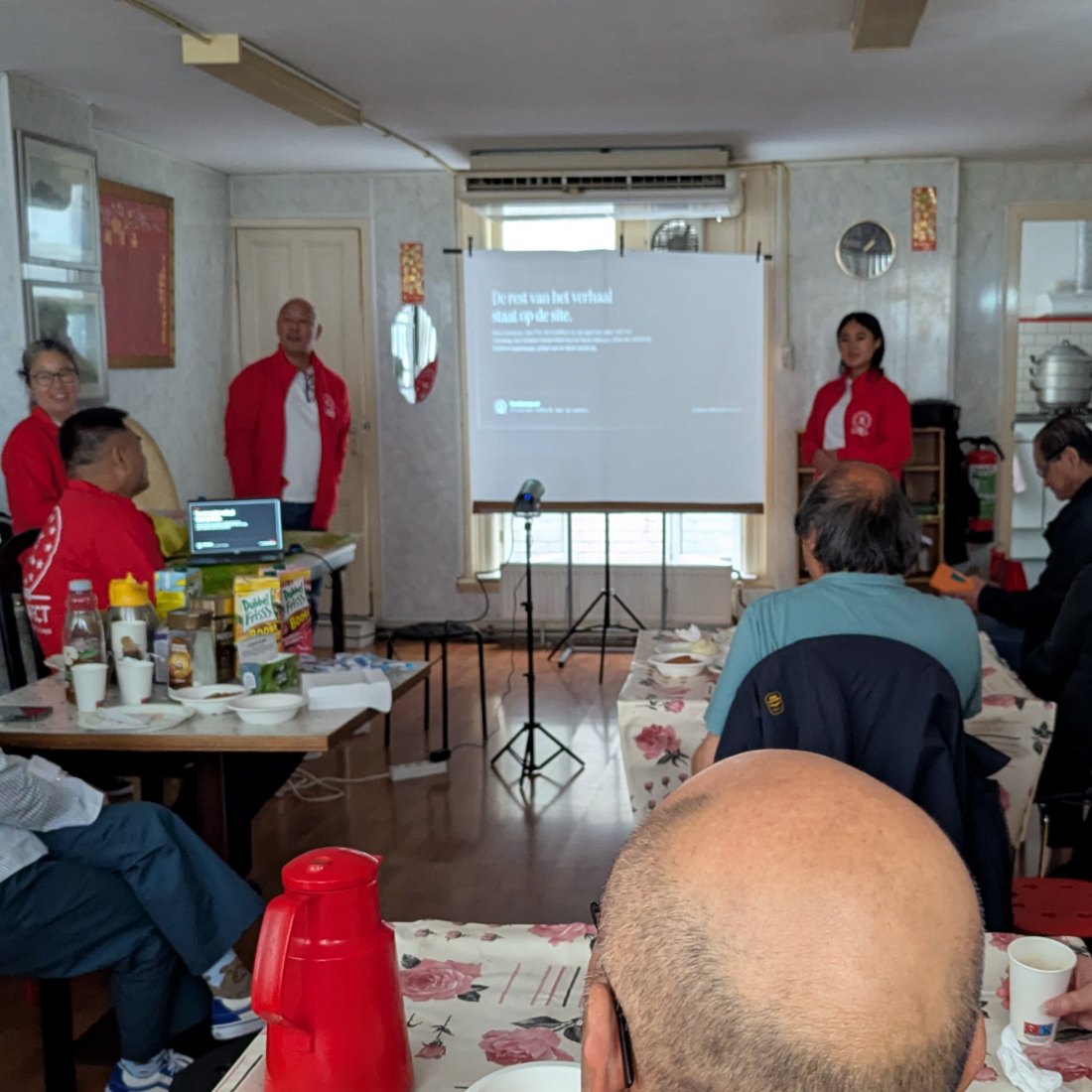 De commissie geeft de presentatie in het clubhuis; op het scherm de slide De rest van het verhaal staat op de site